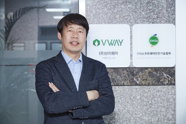 ㈜브이웨이·소프트웨어안전기술협회 현판 앞에서 팔짱을 낀 노경현 대표