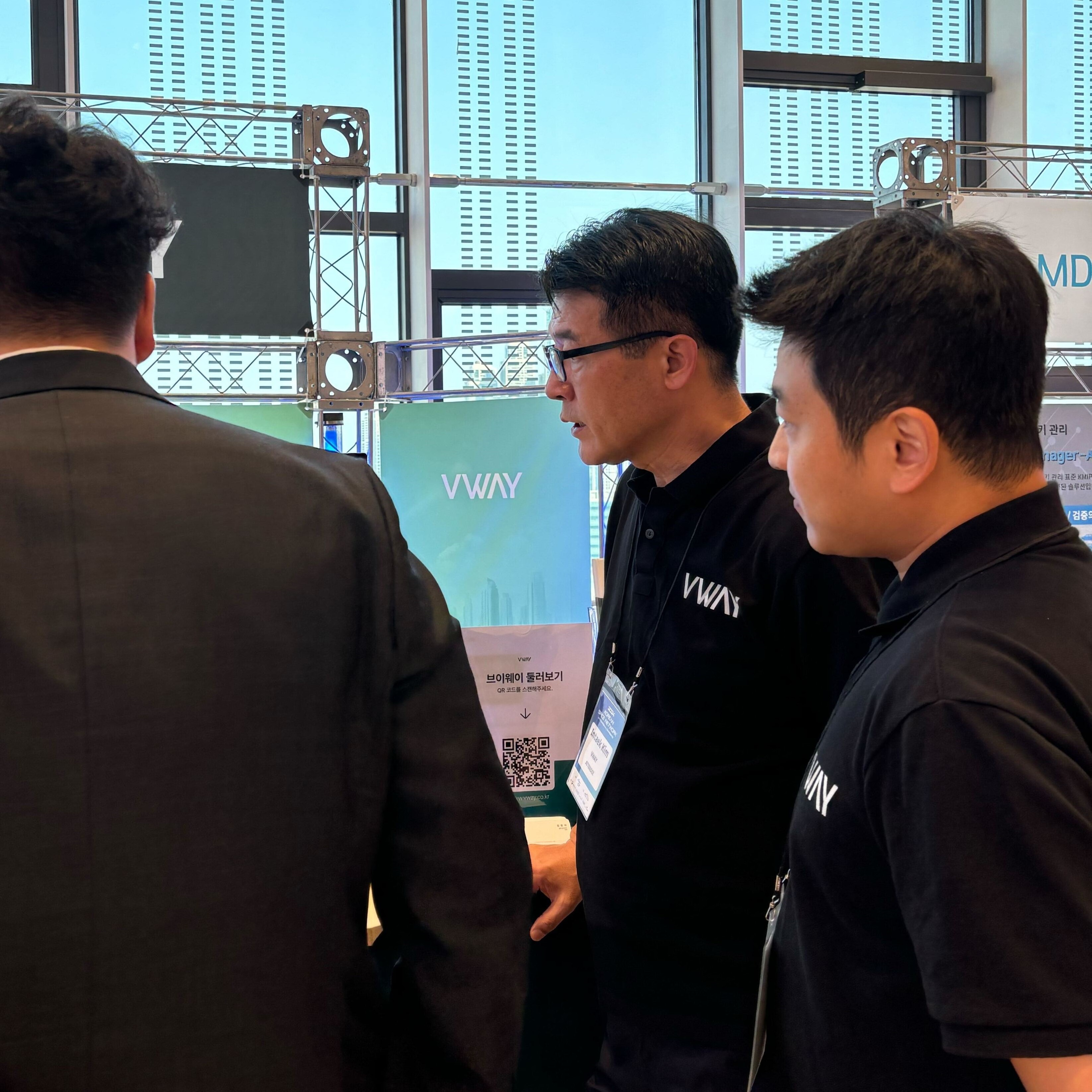 2024 KSN International Conference 브이웨이 부스에서 방문객과 상담하는 모습 — 뒤편에 VWAY 배너와 '브이웨이 둘러보기' QR 코드 안내판