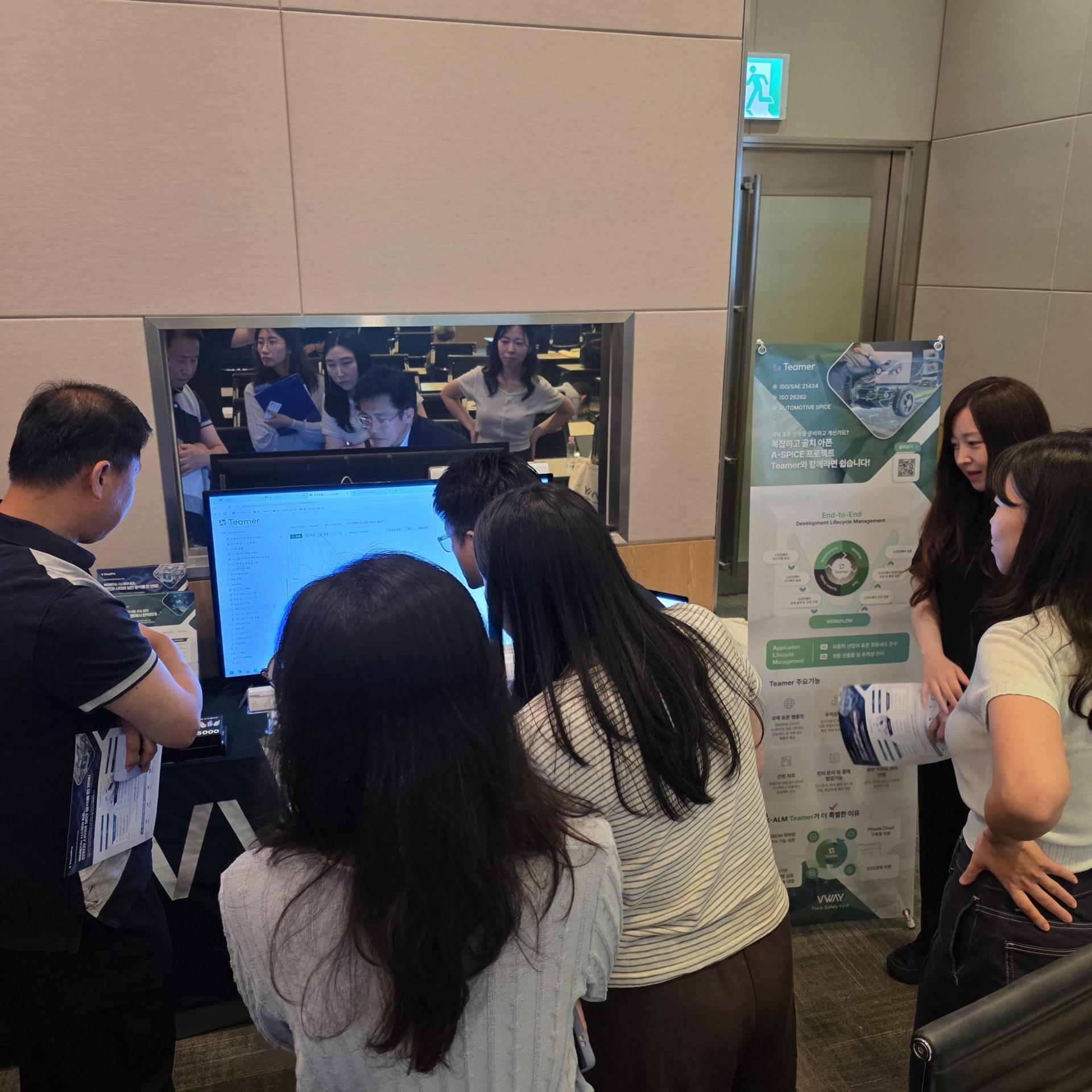 IAR Korea Embedded Conference 2026 로비의 브이웨이 부스 — 참관객들이 모니터 앞에서 설명을 듣는 모습