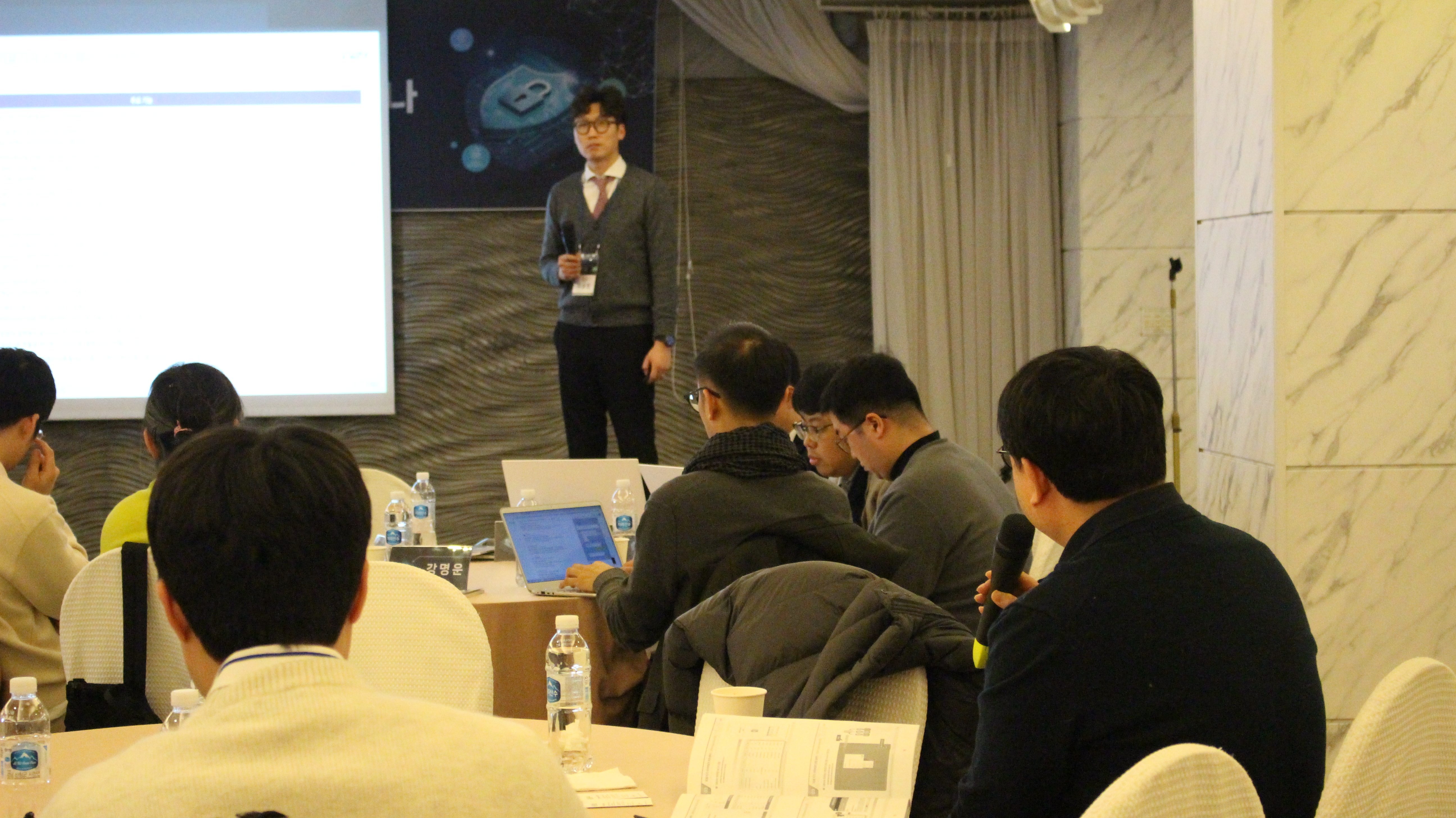 스마트 의료안전 컨퍼런스 2024 강연 장면 — 발표자가 화면을 가리키며 설명하고 참석자들이 노트북으로 따라가는 모습