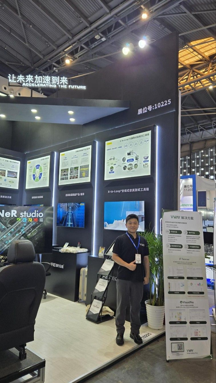 Testing Expo 2025 IAE Group 부스에 함께 전시된 브이웨이 안내판 앞의 직원 — VWAY 解决方案(솔루션) 패널에 자동차·의료·항공우주·IT 산업별 대응(ISO 26262·ASPICE·ISO/SAE 21434, IEC 62304·ISO 13485, DO-178C, ISO 21434)과 Teamer·VisualPro(STPA·FMEA·FTA·TARA) 소개