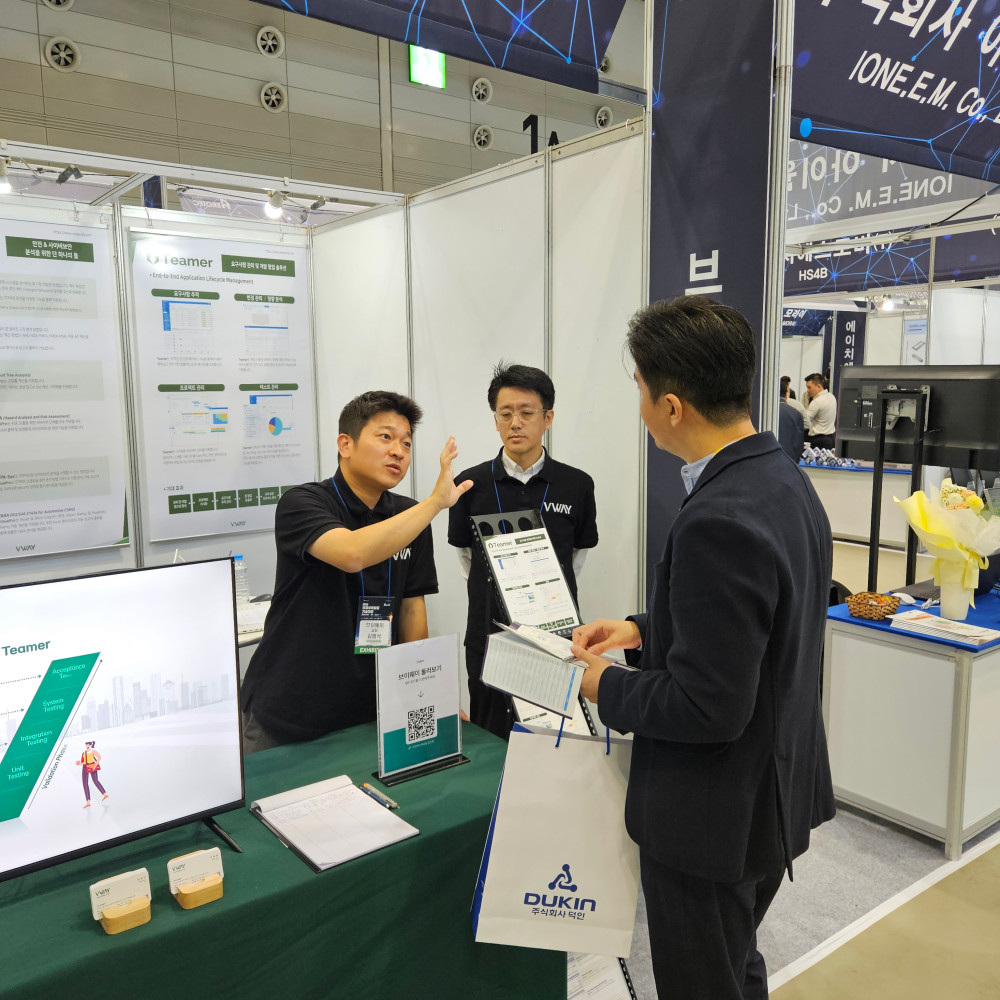 AEROTEC 2024 브이웨이 부스 상담 장면 — Teamer 요구사항 관리 및 개발 협업 솔루션 패널과 V 모델(Unit Testing·Integration Testing·System Testing·Acceptance Test) 화면