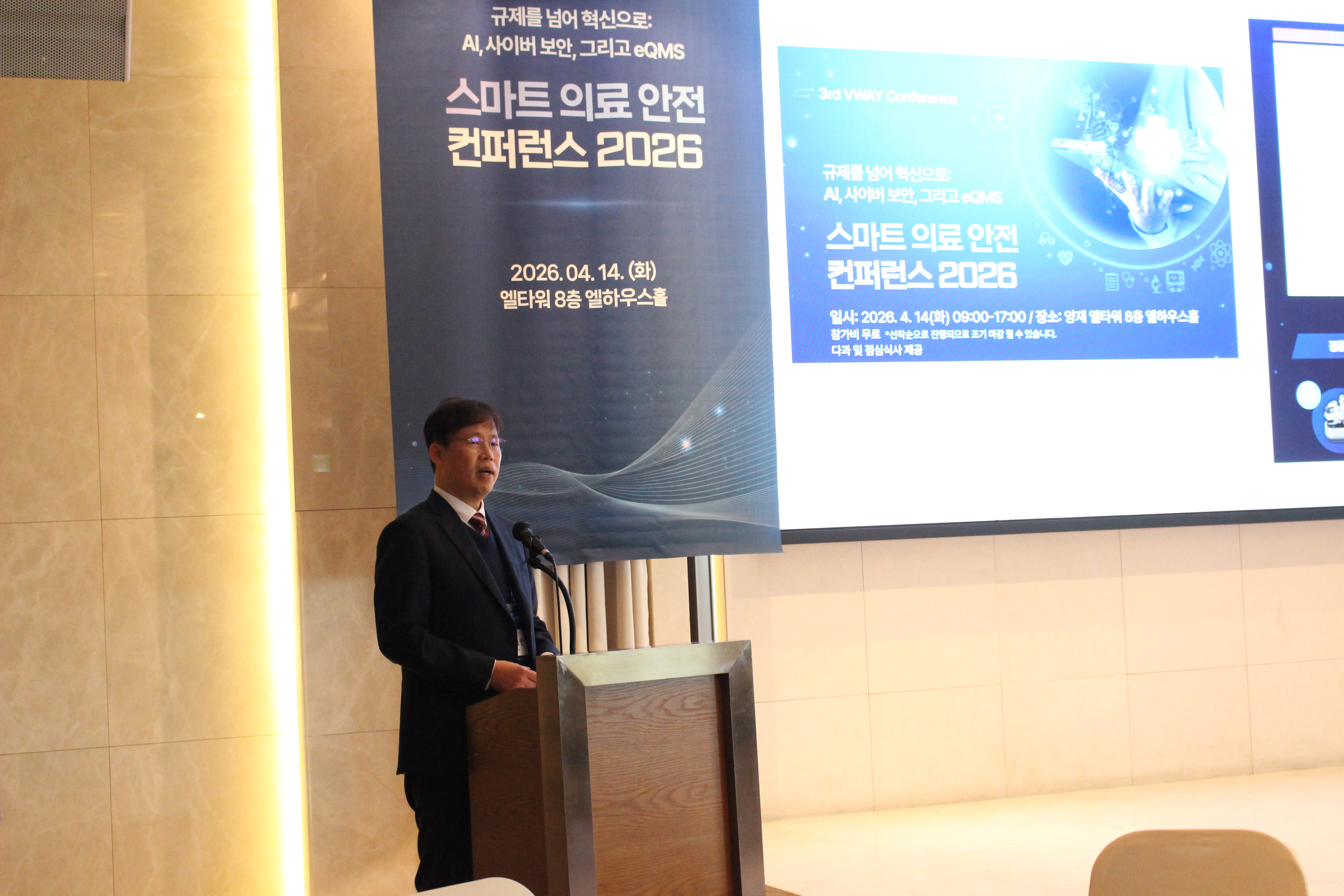 VWAY 스마트 의료 안전 컨퍼런스 2026 에서 노경현 대표가 개회사와 기조연설을 하는 모습, 뒤 화면에 2026.04.14 행사 표지