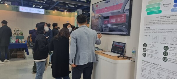 전시회 브이웨이 부스에서 관람객들이 패널과 모니터를 보는 모습